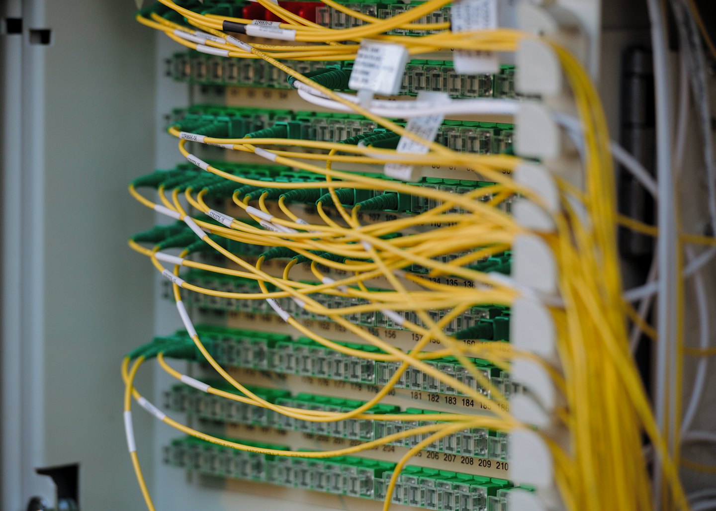 Yellow fiber optic cables plugged into data center patch panels.