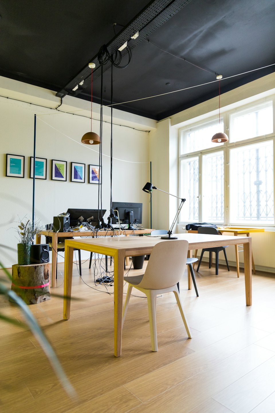 Modern office with light wood desks and large windows.