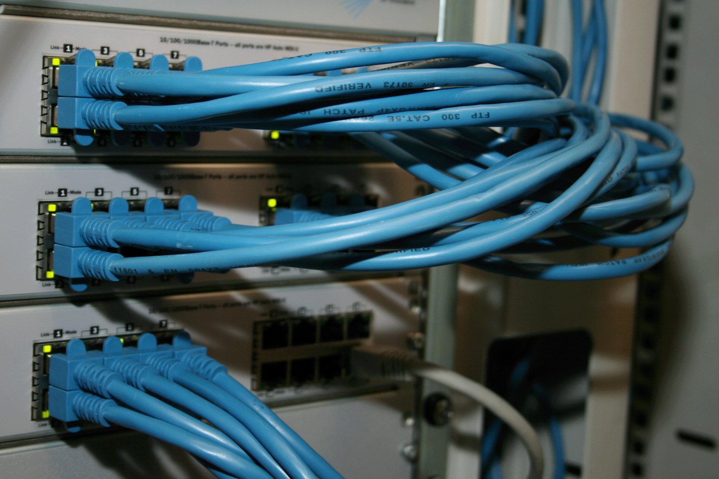 Blue Ethernet cables plugged into grey network switches.